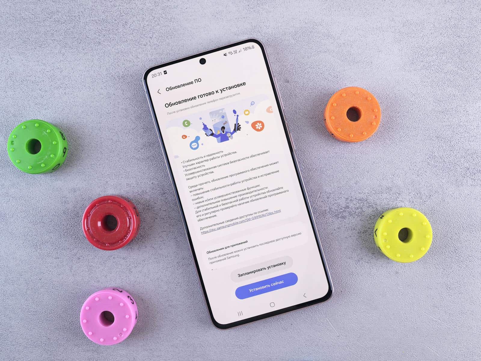 Flat lay of a smartphone displaying a software update, surrounded by colorful toy accessories on a gray desk. update software