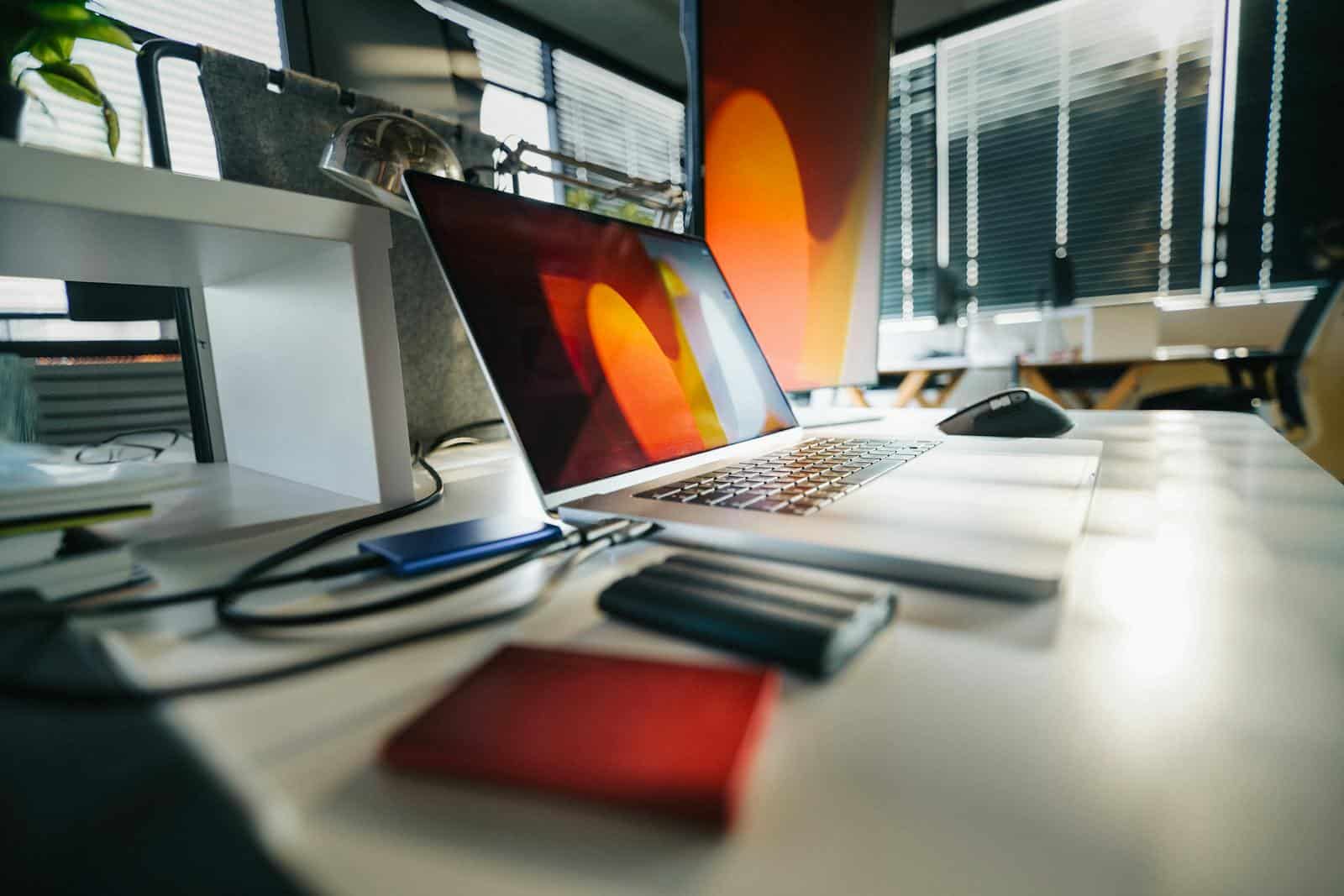 A modern workspace featuring a laptop, external drives, and office equipment on a desk. backup