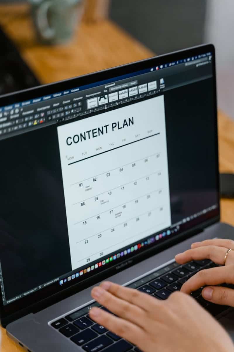 Close-up of hands typing on a laptop displaying a content plan document, ideal for business or marketing content. User Experience with Effective Information Architecture