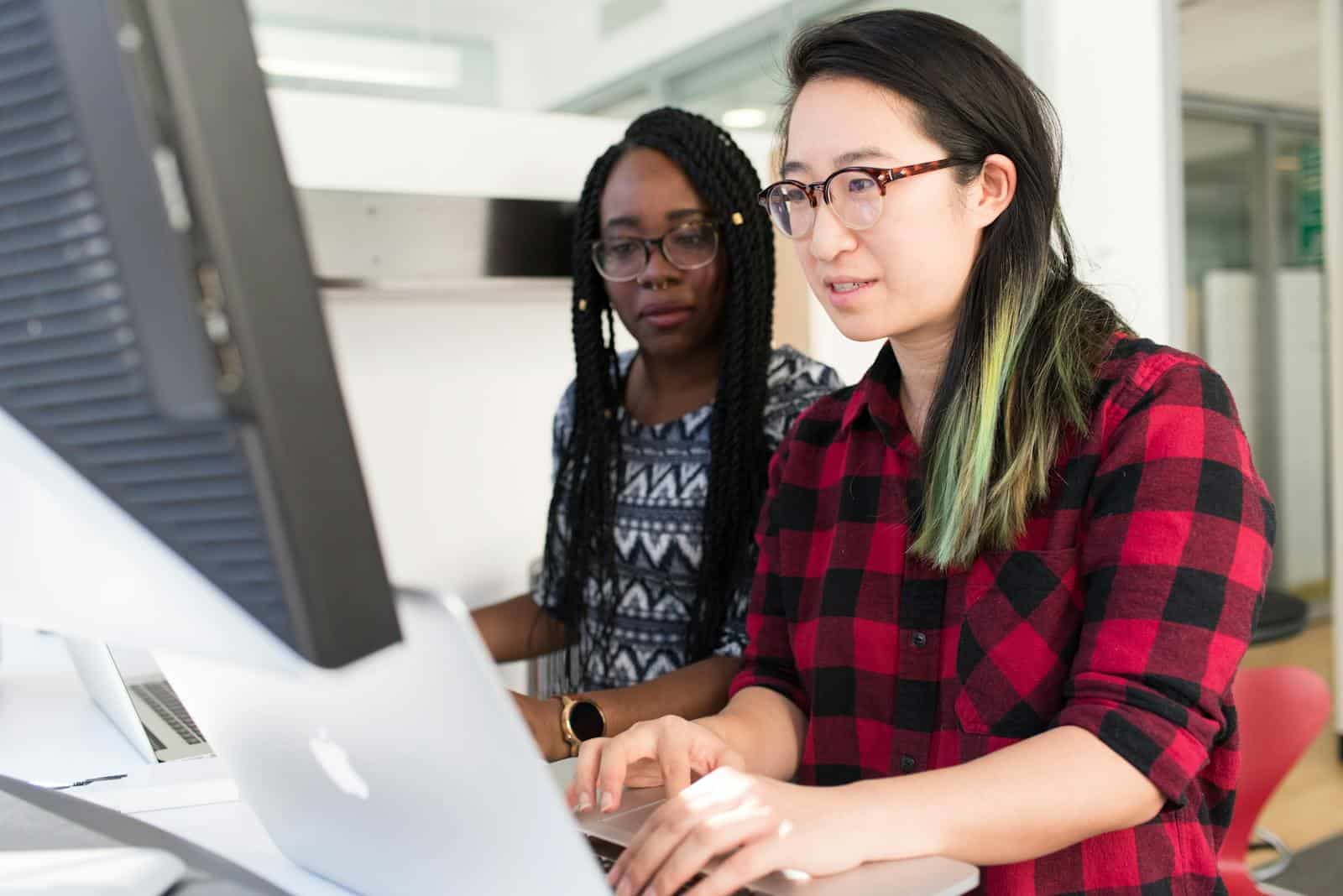 Website Plugin, Two women working on a computer project together in an office setting.