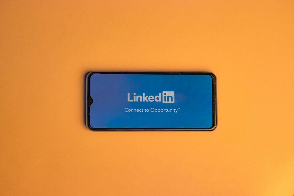 Linkedin, Group, Networking, Lead Generation, Networking, Smartphone showing LinkedIn login on vibrant orange background, symbolizing connectivity.