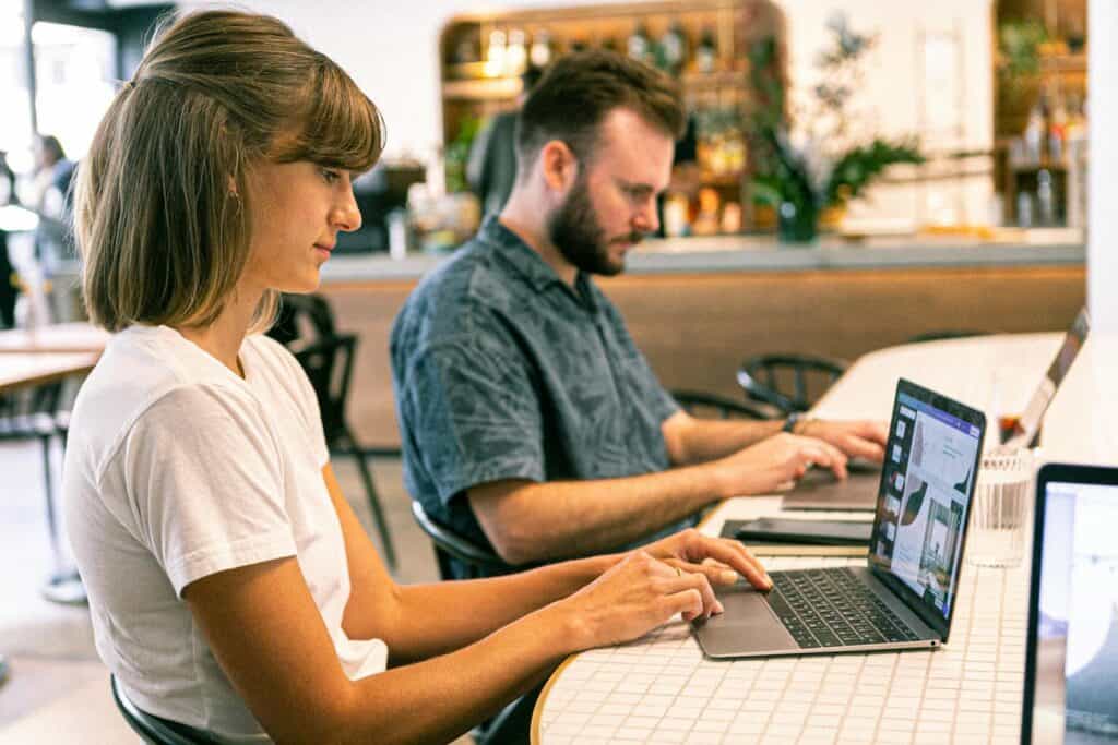 Maximizing Your Online Presence with a Digital Marketing Agency, Two young professionals working on laptops in a modern cafe setting.