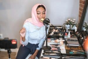 Leveraging Influencer Marketing for Success. A vlogger in a stylish hijab records a makeup tutorial with a microphone. Fashion and beauty focus.