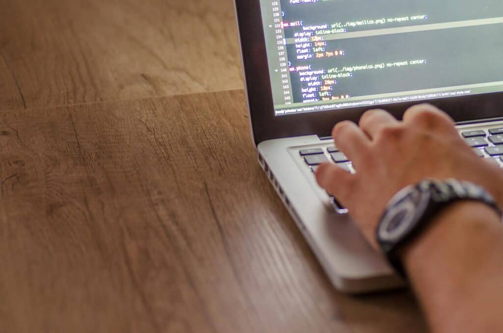 Website Plugin, Close-up of a person coding on a laptop, showcasing web development and programming concepts.