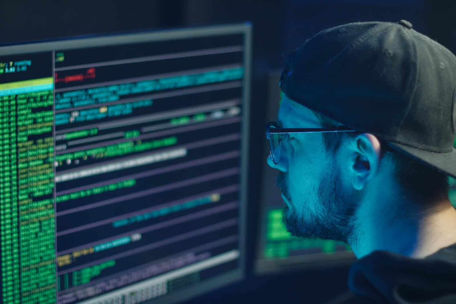 Website, Plugin, A cybersecurity expert inspecting lines of code on multiple monitors in a dimly lit office.