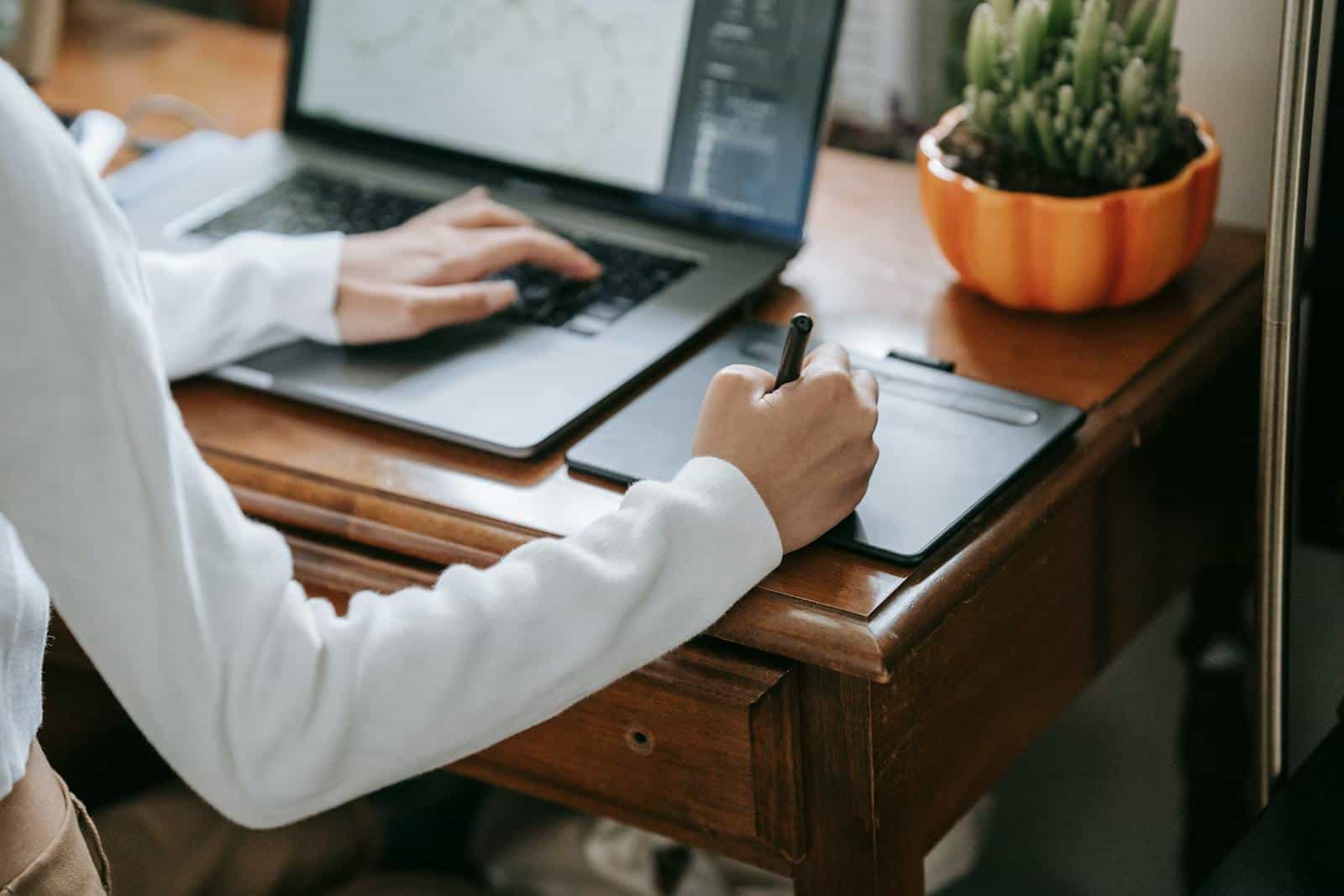 digital illustration highlights and shadows, 
Close-up of designer working on graphics tablet with laptop, enhancing creativity and digital work.
