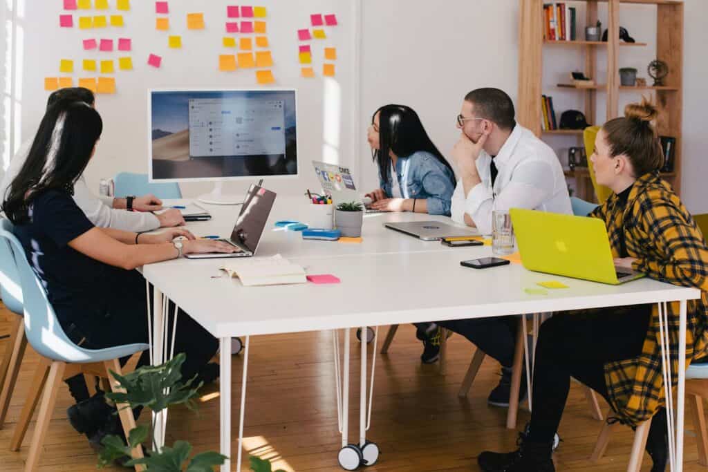 Market Research, five person by table watching turned on white iMac