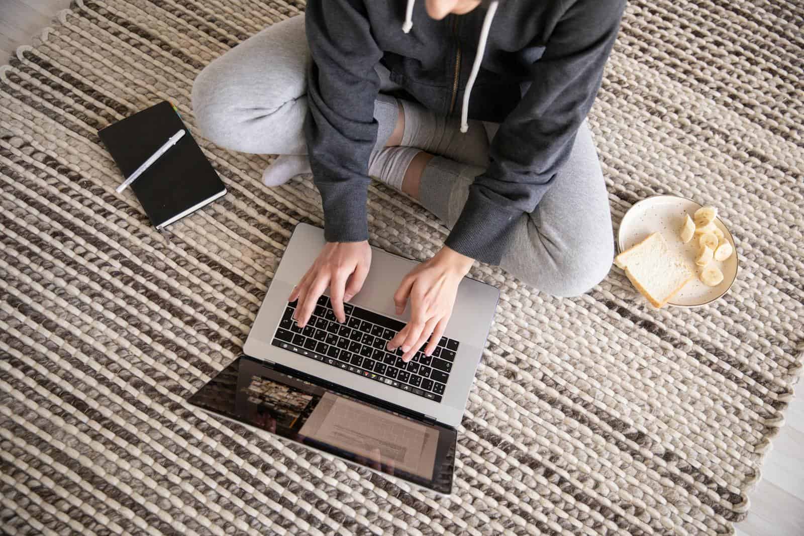 Build Your Email List: Get More Subscribers Now, Woman in casual wear working remotely on a laptop, with a notebook and snack nearby.