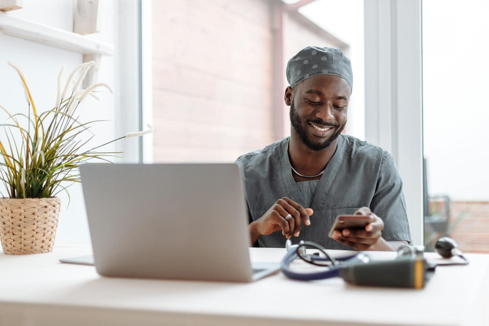 Email, Marketing, Subject line, engagement, Smiling healthcare professional using phone in office with laptop and medical tools.
