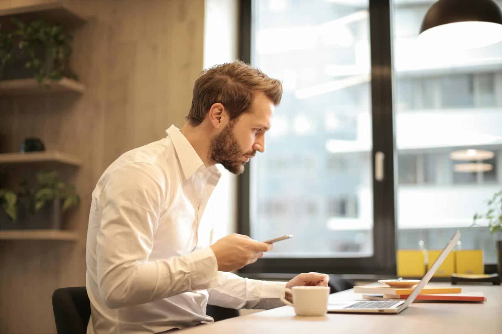 Lead Magnet, b2b marketing, lead generation, sales funnel, digital marketing, case studie, white paper, subscriber list building, Focused businessman working on laptop while checking smartphone in modern office.