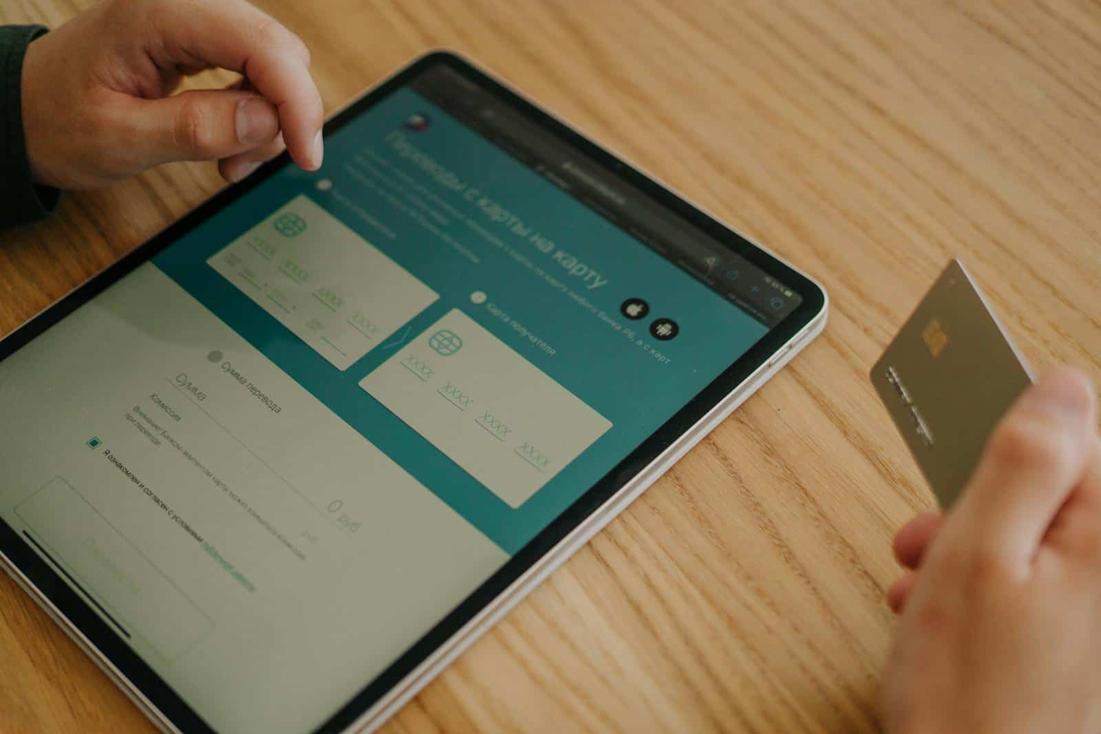 Conversions, Fluent, Forms, Website, Development, Design, Hosting, Tech Stack, Traffic, Subscribers, Contact, Hands making an online purchase using a tablet and credit card on a wooden table.