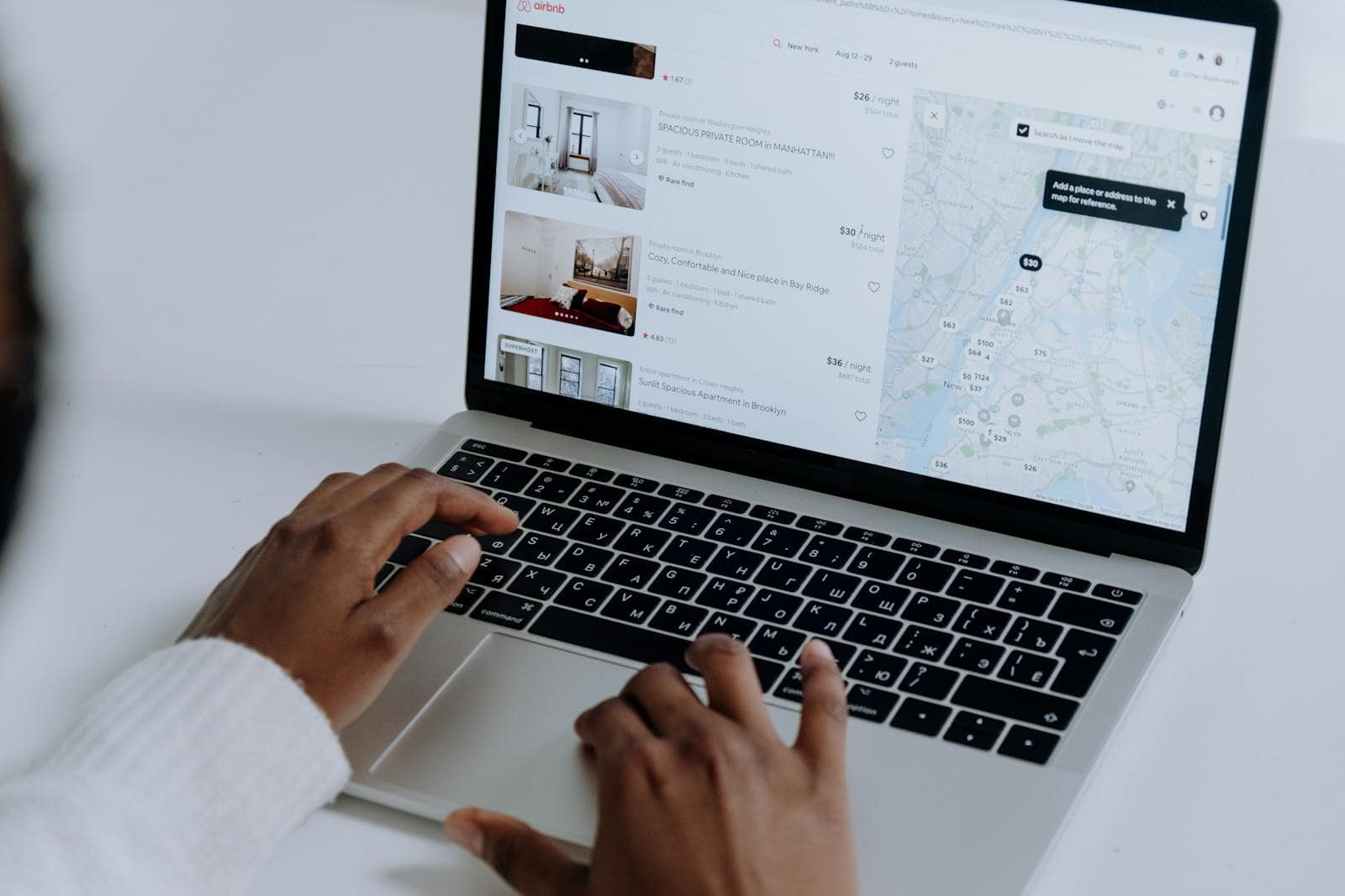 Website traffic, Squirrly SEO Plugin, Online Marketing, Hands typing on laptop searching Airbnb for accommodation options with map view.