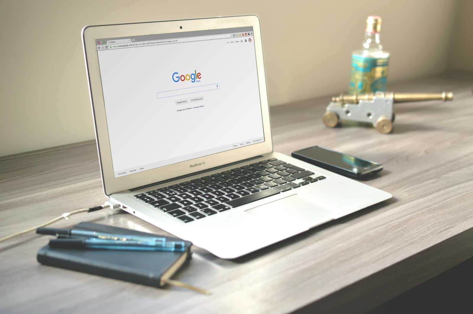 Website traffic, Squirrly SEO Plugin, Online Marketing, A neat workspace featuring a laptop displaying Google search, a smartphone, and a notebook on a wooden desk.