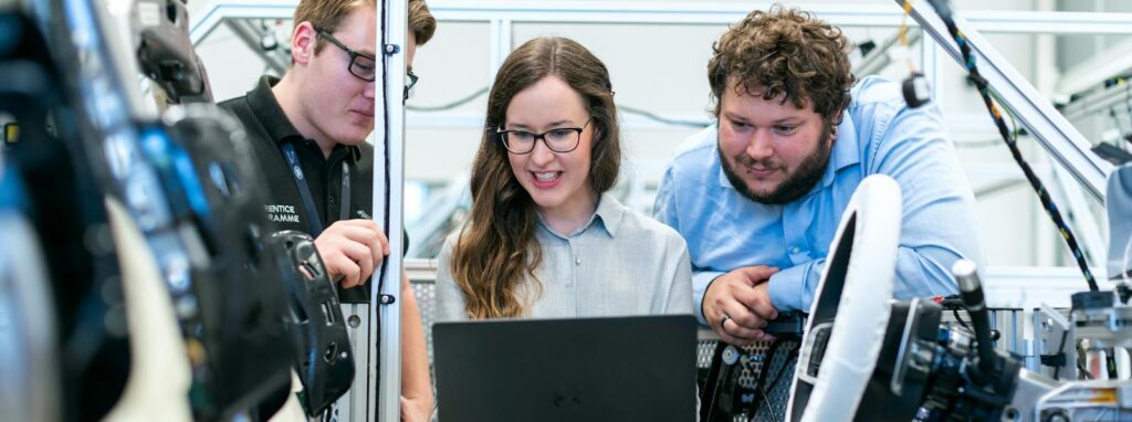 Engineers collaborating on a car project in a modern automotive workshop using advanced technology. business automation ai