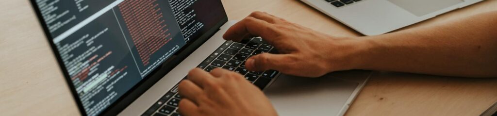 A developer working on a laptop, typing code, showcasing programming and technology skills.