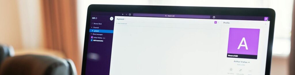 Person using a laptop with an online communication platform, showcasing modern work tech.